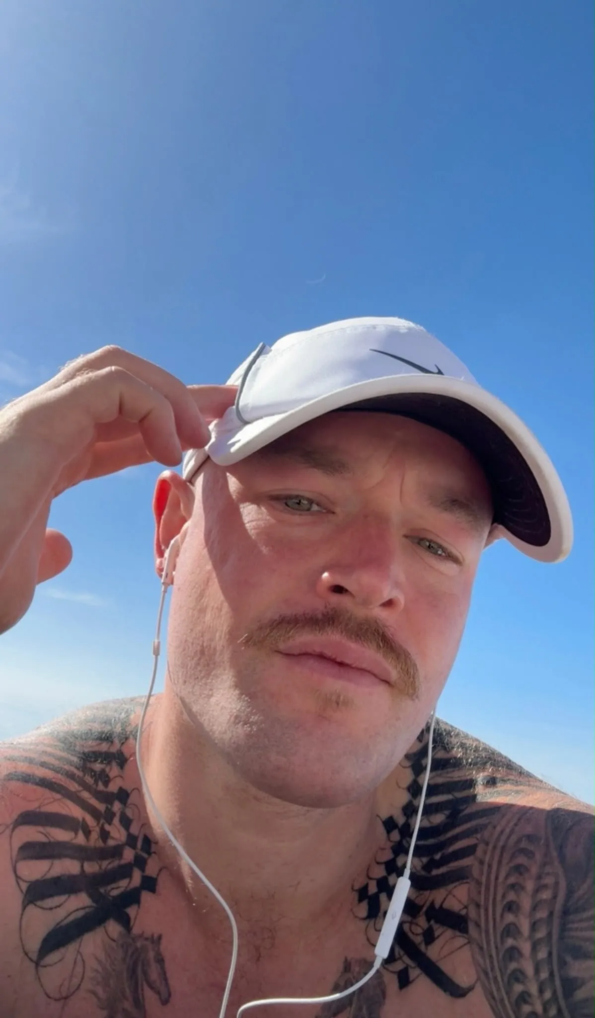 DrhorseJuice outdoors in a white cap, squinting against a blue sky